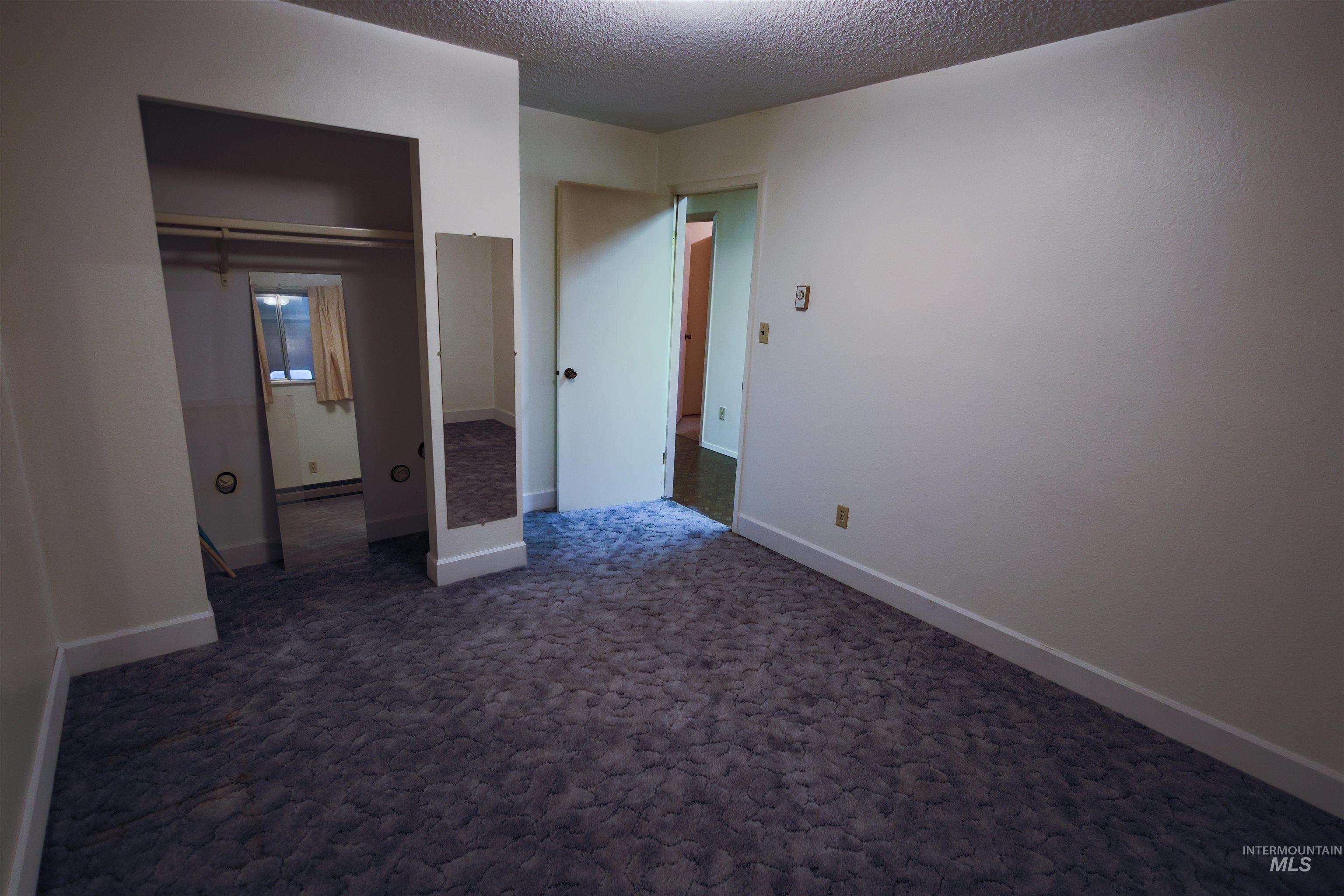 717 Big Cedar Road Kooskia, ID 83539 - Photo 22 of 50 Unfurnished bedroom featuring dark carpet, a textured ceiling, a baseboard heating unit, and a closet