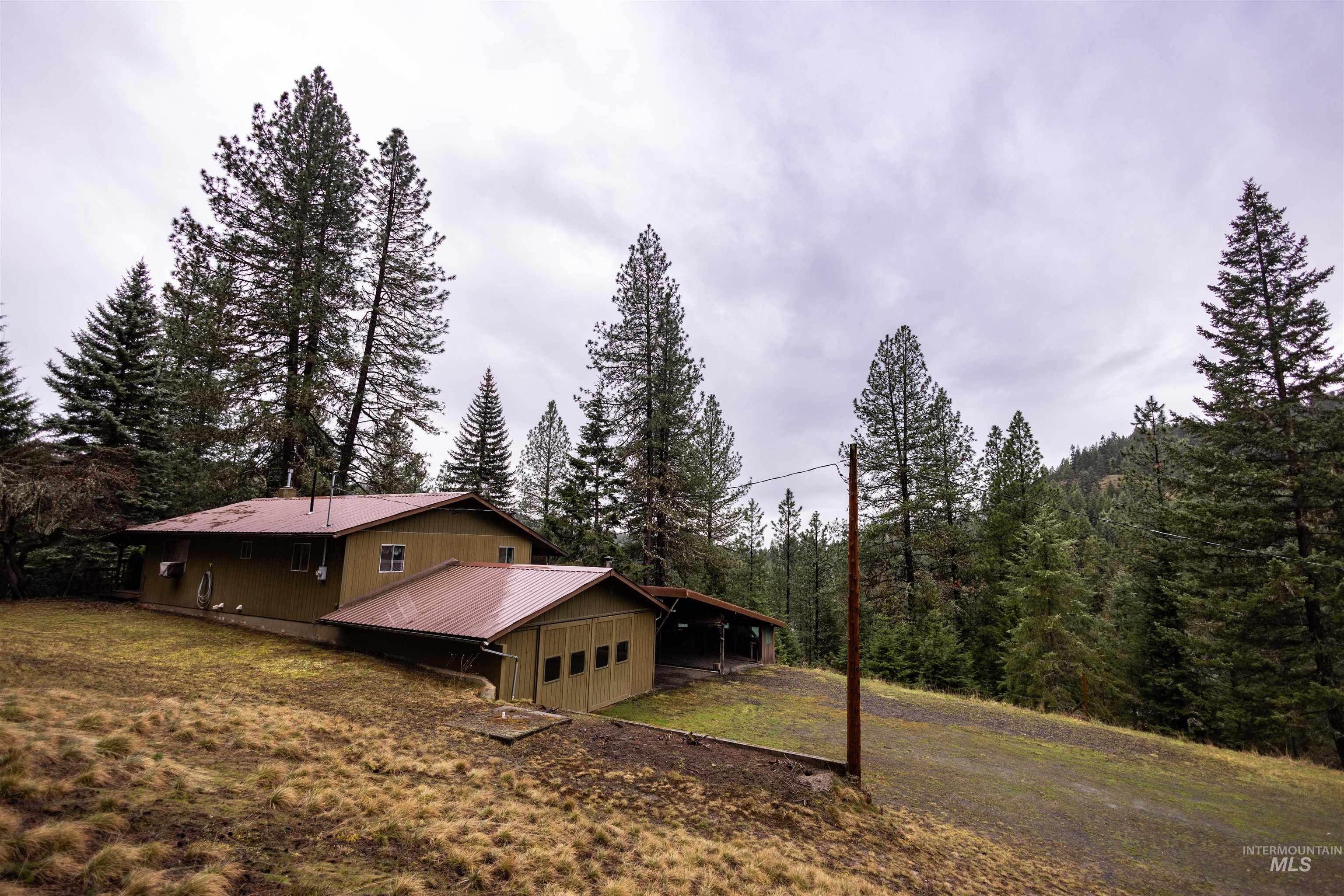 717 Big Cedar Road Kooskia, ID 83539 - Photo 33 of 50 View of side of property with a yard, a garage, a carport, a metal roof, and driveway