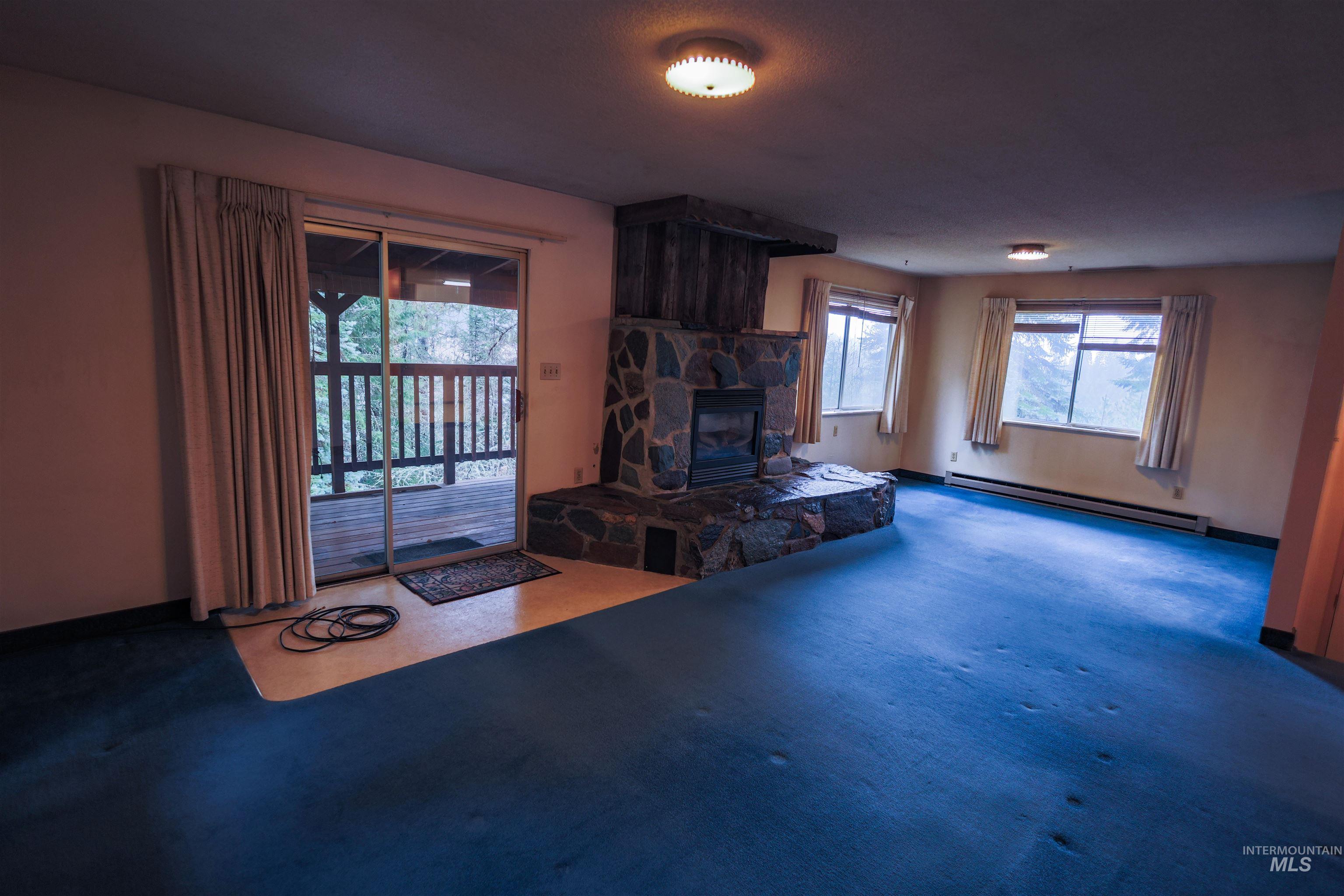 717 Big Cedar Road Kooskia, ID 83539 - Photo 5 of 50 Carpeted living room featuring baseboard heating and a stone fireplace