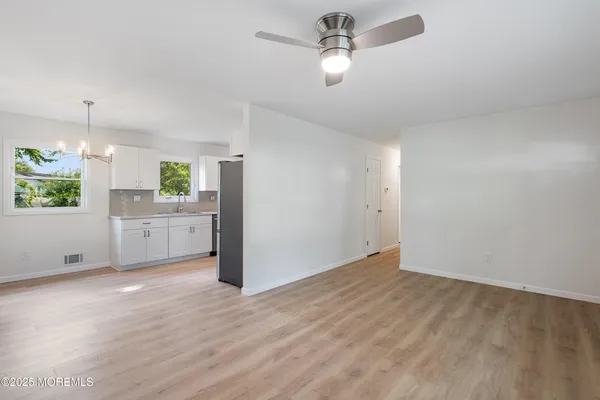 a view of an empty room with window and wooden floor
