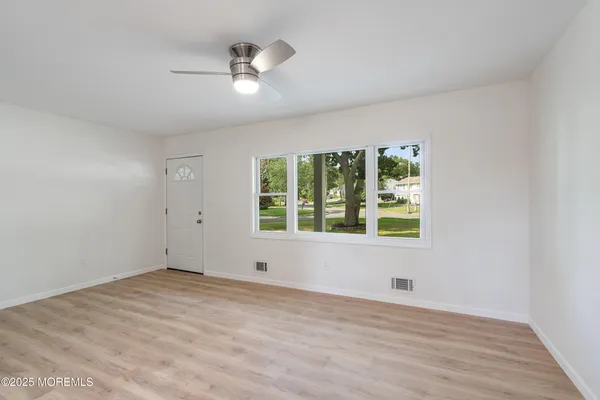 a view of an empty room with a window and wooden floor