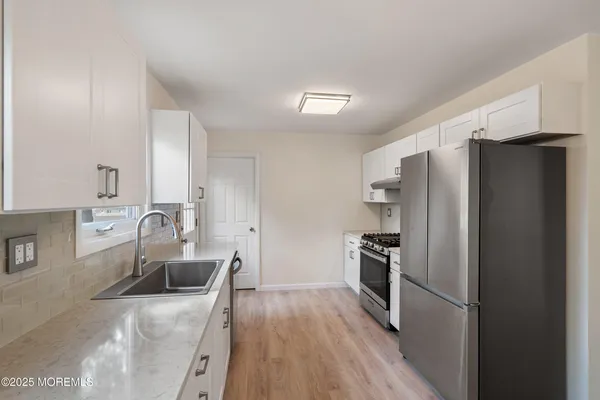 a kitchen with granite countertop stainless steel appliances a refrigerator a stove top oven and sink