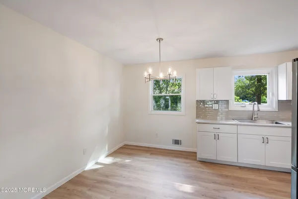 a view of a kitchen with a sink wooden cabinets and a window