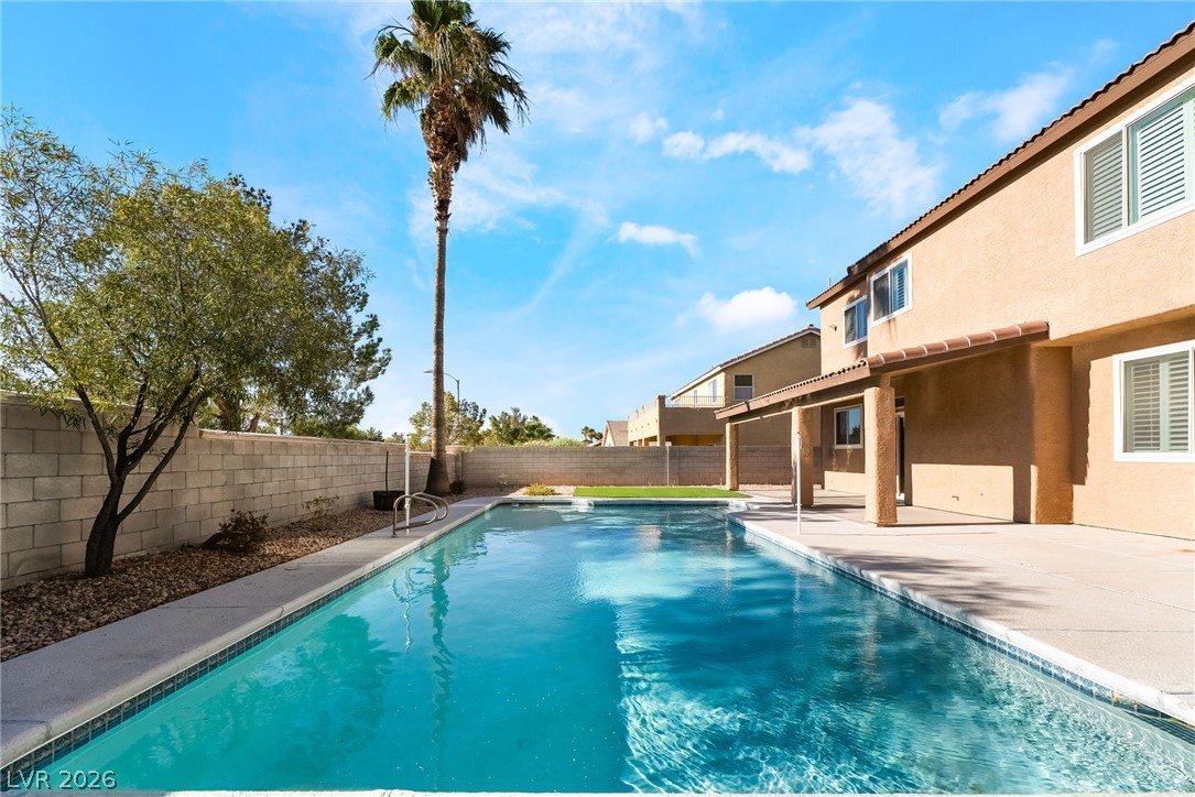 261 Timber Hollow Street Henderson, NV 89012 - Photo 2 of 51 A spacious backyard oasis features a shimmering in-ground pool, covered patio, and low-maintenance landscaping.