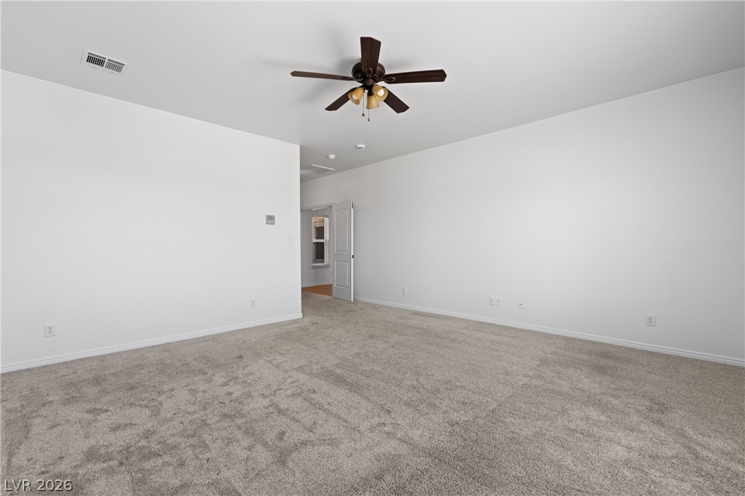 575 Gann Avenue Logandale, NV 89021 - Photo 32 of 75 A spacious room offers ample potential for personalization, featuring plush carpeting and a ceiling fan.