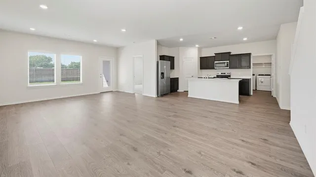 a view of kitchen with stainless steel appliances kitchen island wooden floors and white walls