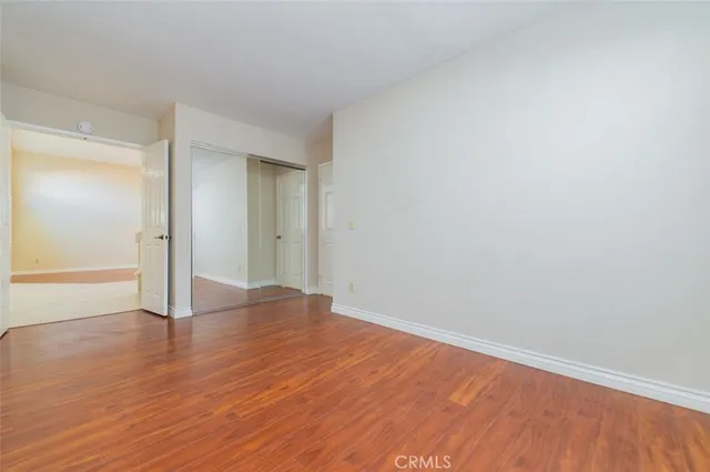 a view of an empty room with wooden floor and closet