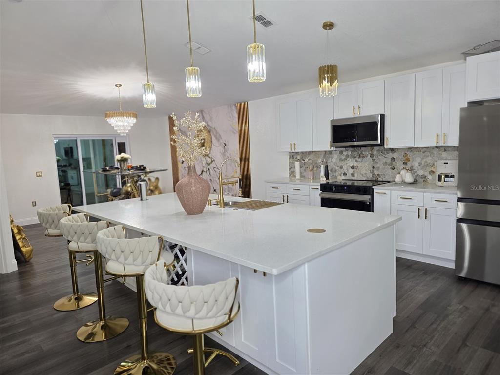 24921 Ravello Street Land O Lakes, FL 34639 - Photo 19 of 36 a kitchen with stainless steel appliances kitchen island granite countertop a sink a microwave a dining table and chairs