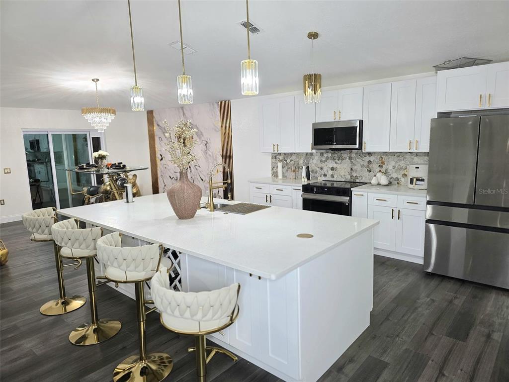 24921 Ravello Street Land O Lakes, FL 34639 - Photo 29 of 36 a kitchen with stainless steel appliances kitchen island granite countertop a dining table and chairs