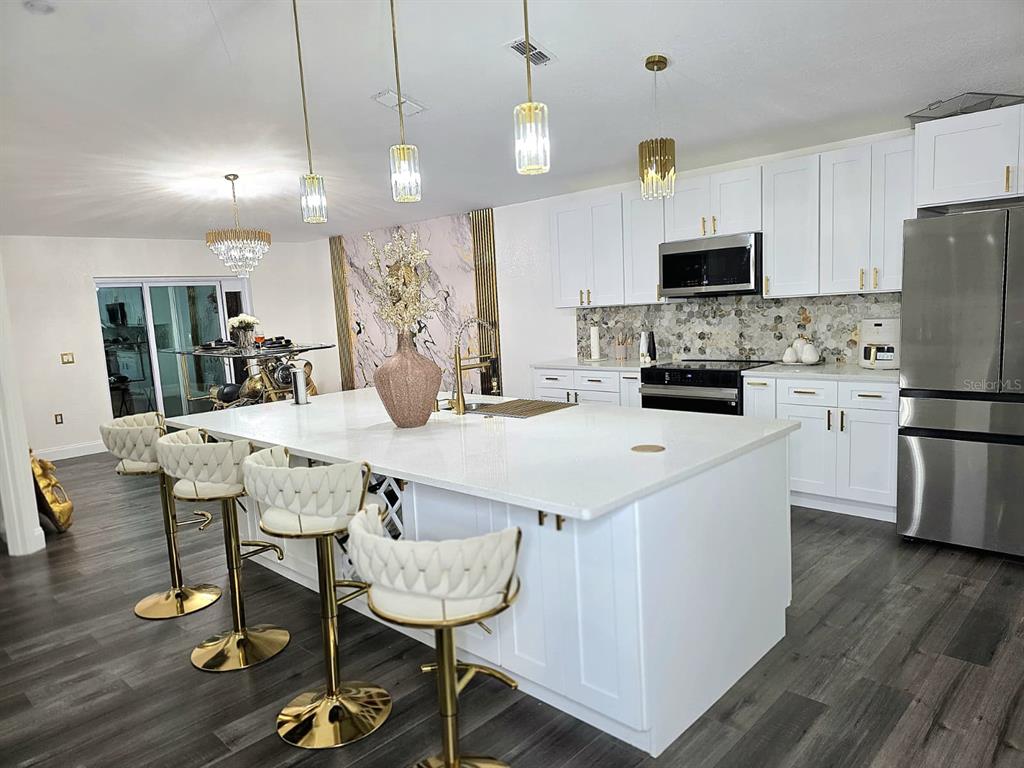 24921 Ravello Street Land O Lakes, FL 34639 - Photo 3 of 36 a kitchen with stainless steel appliances kitchen island granite countertop a dining table chairs refrigerator and microwave