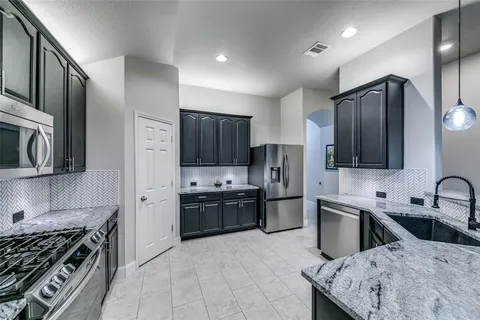 a kitchen with stainless steel appliances granite countertop a sink stove refrigerator and cabinets