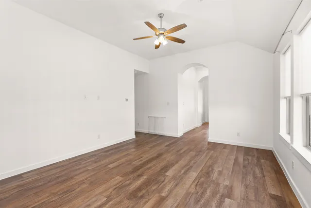an empty room with wooden floor and ceiling fan