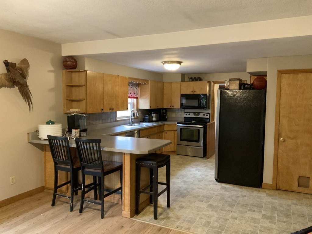 731 Greenfield Road Leyden, MA 01337 - Photo 5 of 36 a kitchen with stainless steel appliances granite countertop a refrigerator a stove a sink a dining table and chairs with wooden floor