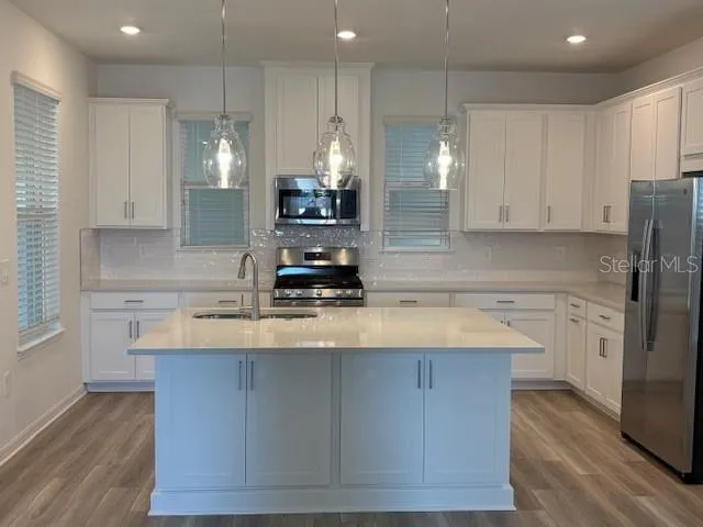 a kitchen with kitchen island granite countertop a sink a center island stainless steel appliances and cabinets