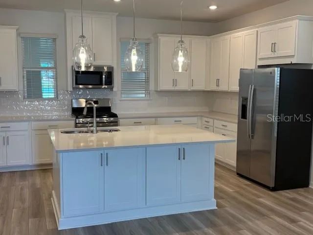 a kitchen with a refrigerator a sink and wooden floor