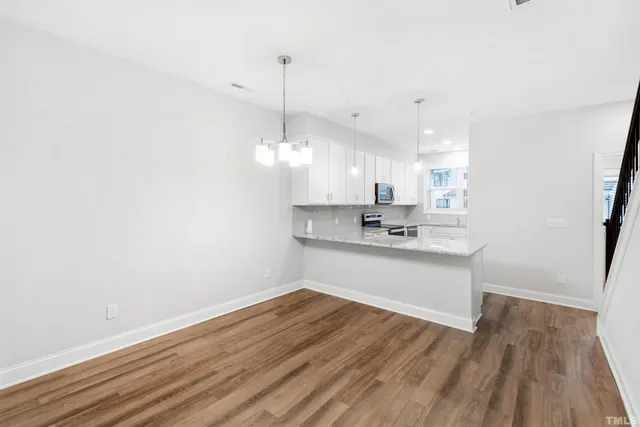a view of a kitchen with a sink and dishwasher with wooden floor