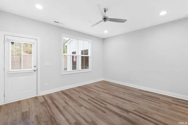 a view of an empty room with wooden floor and a window