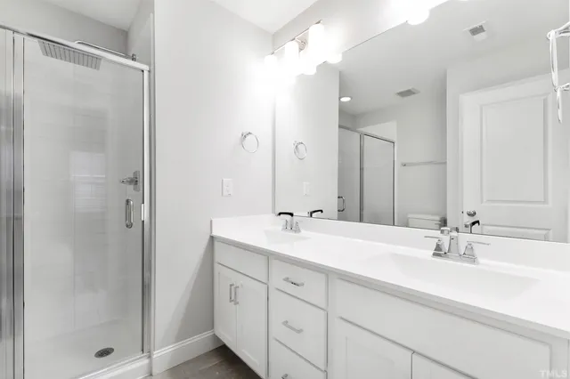 a bathroom with a double vanity sink mirror and shower