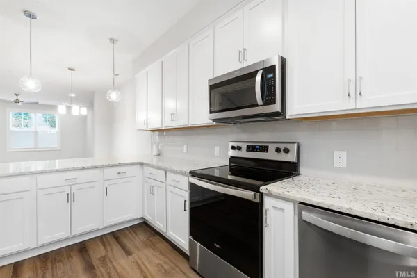 a kitchen with stainless steel appliances granite countertop a sink dishwasher a stove and a microwave oven with white cabinets