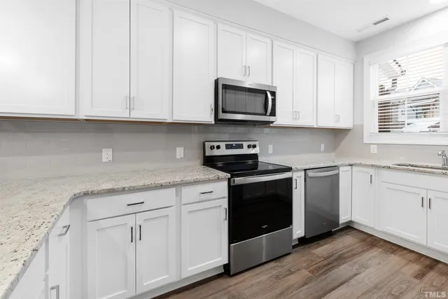 a kitchen with white cabinets and appliances