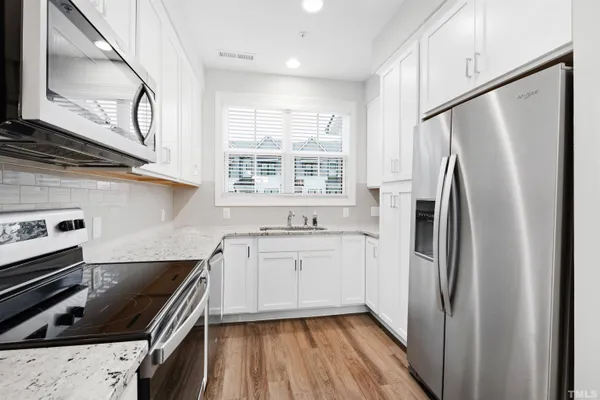 a kitchen with stainless steel appliances a refrigerator a sink a stove and cabinets