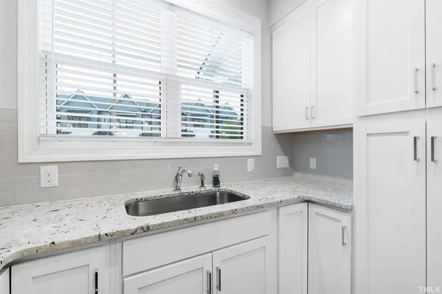 a kitchen with granite countertop white cabinets and a sink