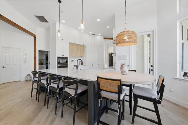 a view of a a dining room and livingroom with furniture wooden floor a chandelier