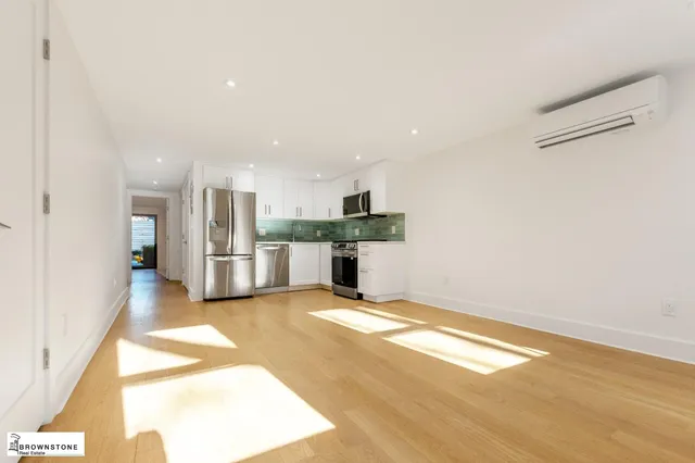 a view of an empty room with kitchen and a window