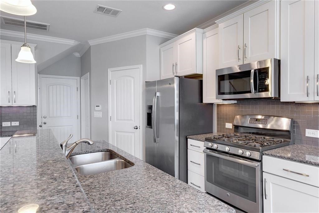 13400 Briarwick Drive, Unit 2502 Austin, TX 78729 - Photo 6 of 20 a kitchen with granite countertop a stove a sink and a microwave