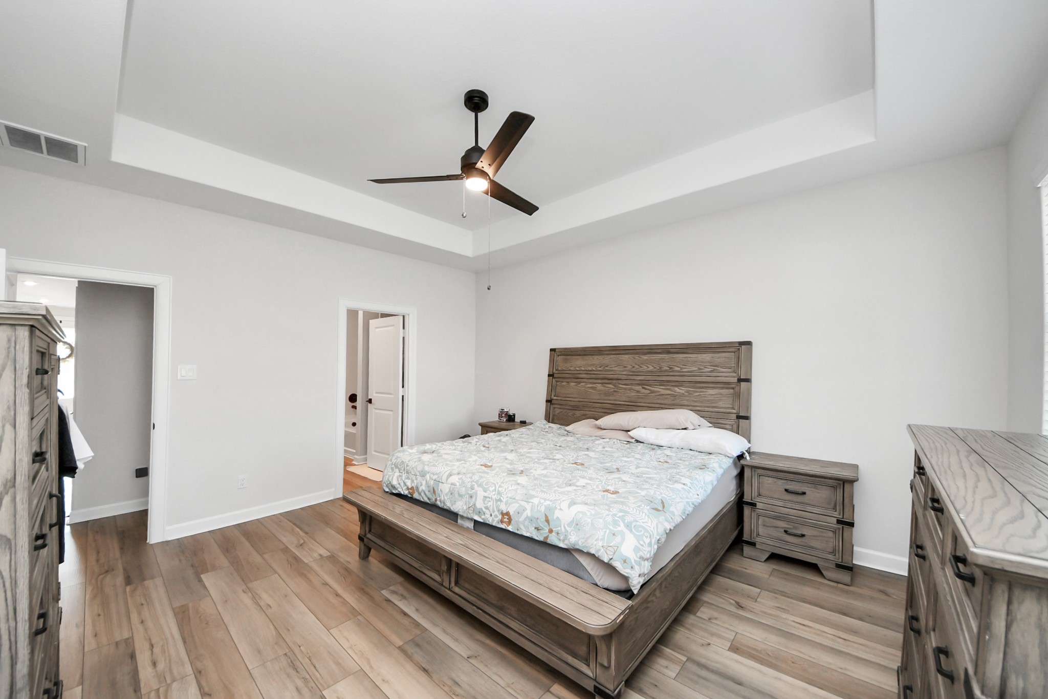 3006 Floating Barque Drive Santa Fe, TX 77510 - Photo 16 of 37 This spacious bedroom features a modern ceiling fan, tray ceiling, and light wood flooring. It includes a large windows creating a bright yet cozy and cohesive primary.