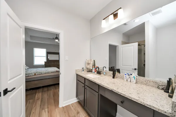 a en suite bathroom with a granite countertop sink and a mirror