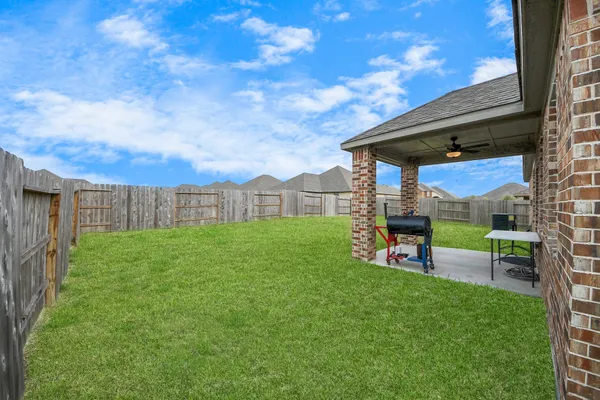 a view of a backyard with table and chairs under an umbrella with wooden fence