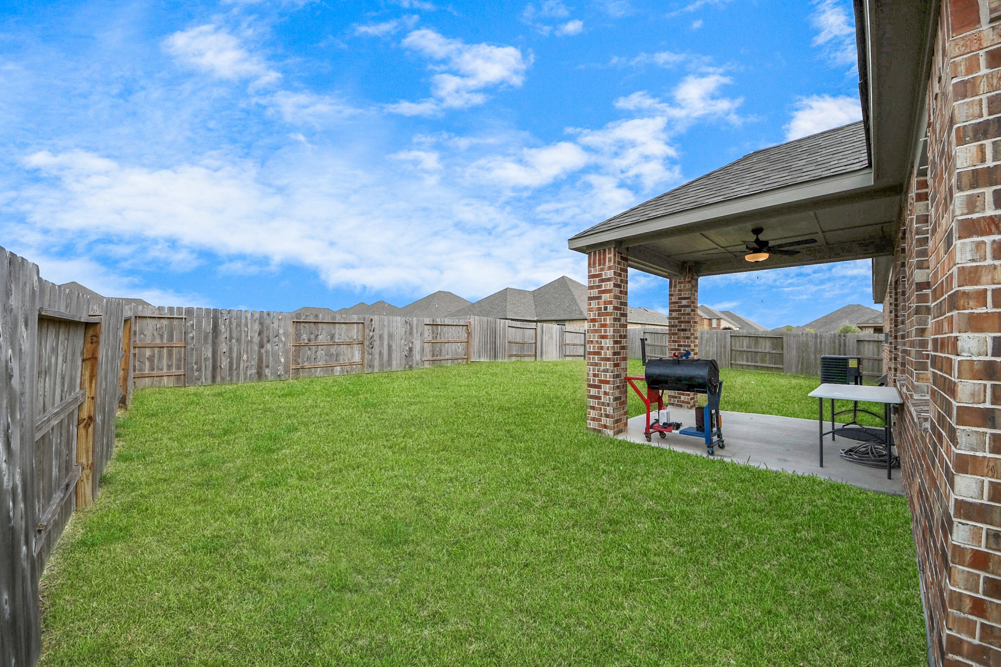 3006 Floating Barque Drive Santa Fe, TX 77510 - Photo 28 of 37 Spacious backyard with a covered patio, perfect for outdoor gatherings. The area is fenced for privacy and features a well-maintained lawn.
