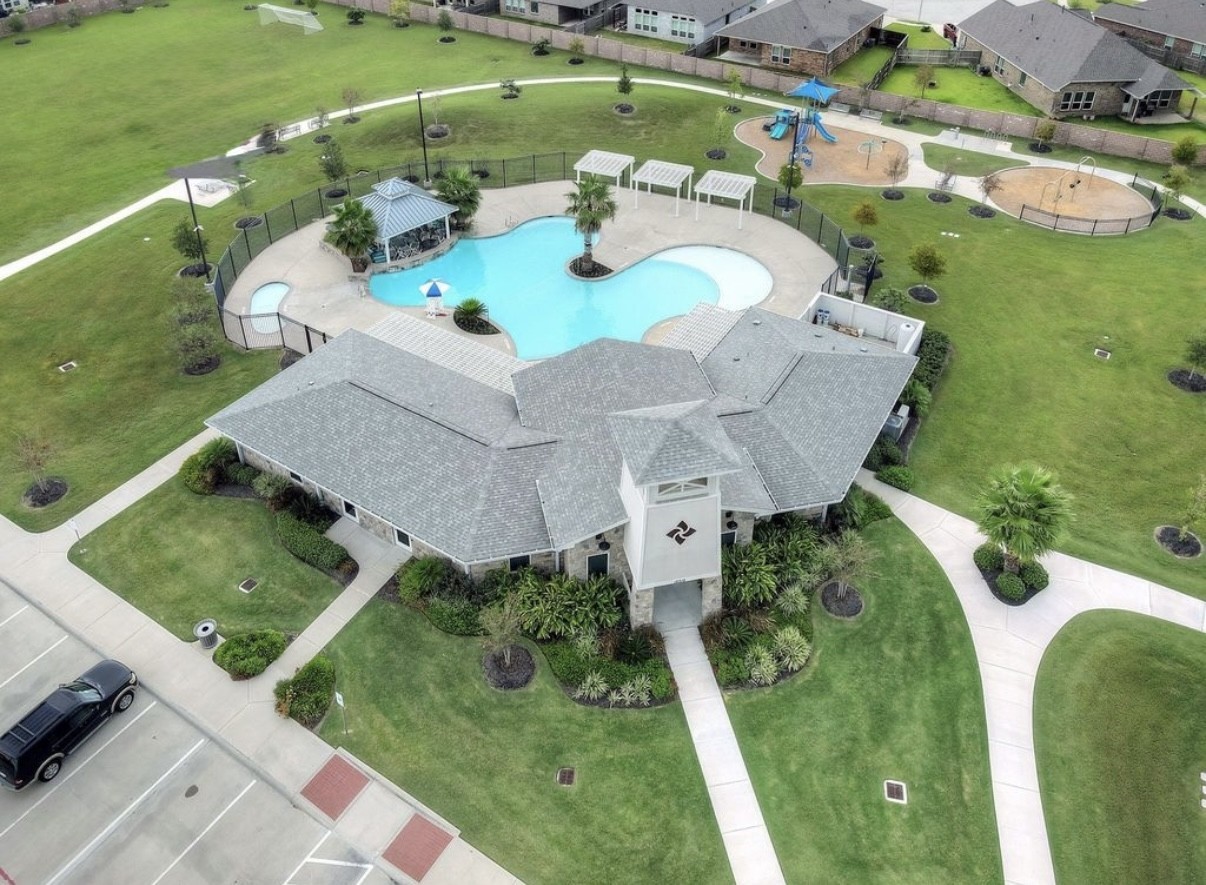 3006 Floating Barque Drive Santa Fe, TX 77510 - Photo 35 of 37 This photo showcases a community recreation area featuring a community center, a pool with lounging space, a gazebo, and a playground, all surrounded by well-maintained green spaces and walking paths.