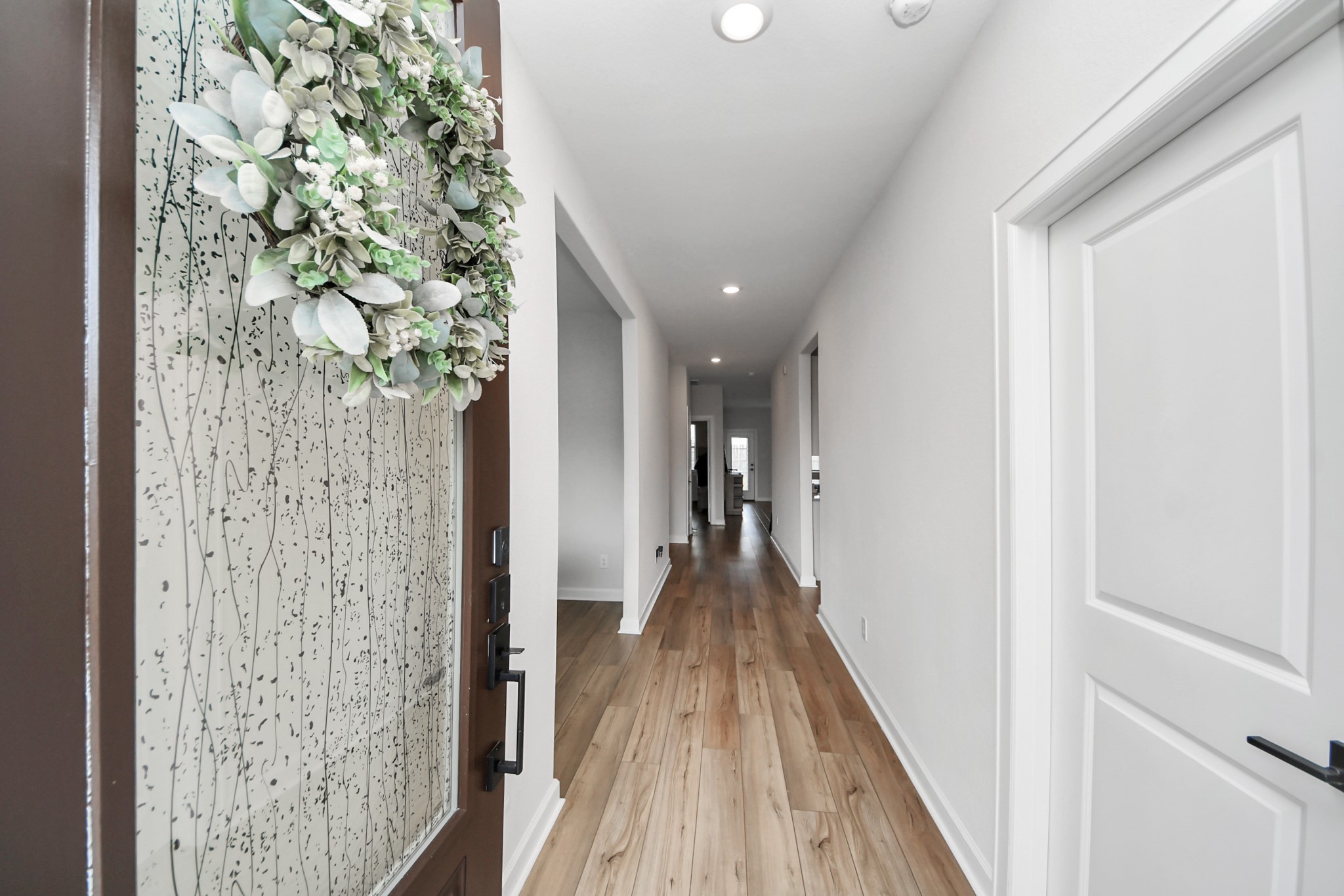 3006 Floating Barque Drive Santa Fe, TX 77510 - Photo 4 of 37 bright, modern entryway with light wood flooring and white walls. The front door features decorative glass. Recessed lighting adds a contemporary touch to the hallway, leading to foyer.