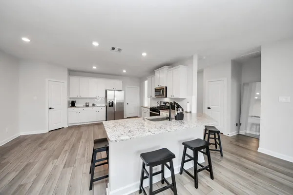 a kitchen with stainless steel appliances kitchen island granite countertop a table chairs microwave and cabinets