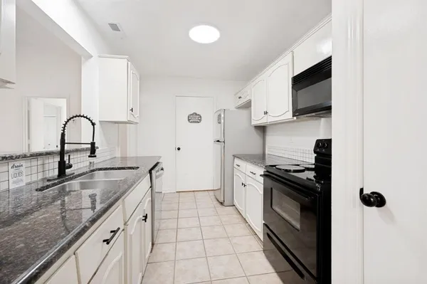 a kitchen with granite countertop a sink stainless steel appliances and white cabinets