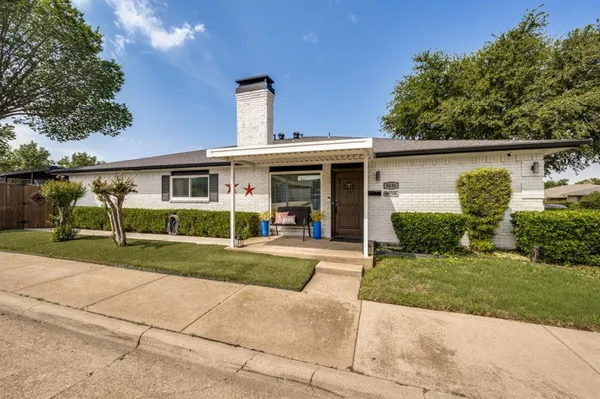 a front view of a house with a yard and potted plants