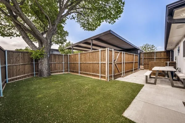 a view of a backyard with wooden fence and a large tree
