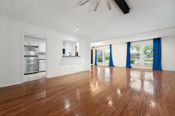 a view of an empty room with window and wooden floor