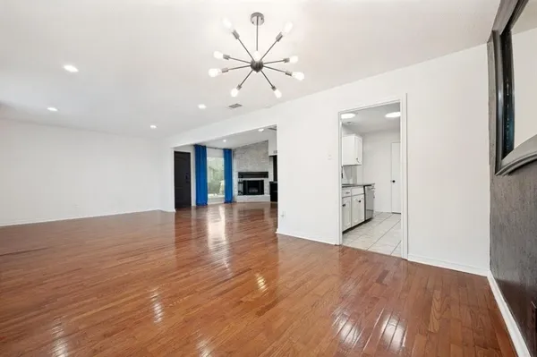 a view of an empty room with wooden floor and a ceiling fan