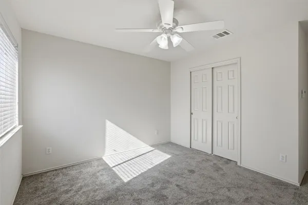 an empty room with a ceiling fan and a window