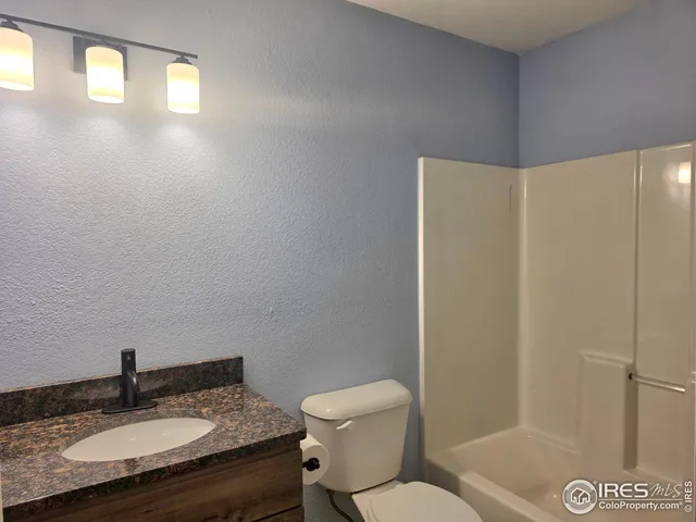 a bathroom with a granite countertop sink toilet a mirror and shower