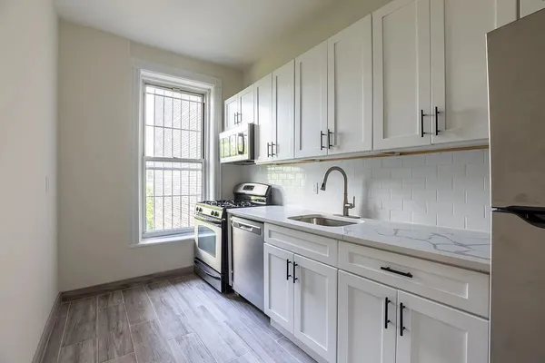 a kitchen with granite countertop stainless steel appliances sink cabinets and window