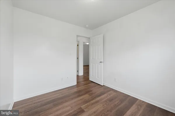 a view of an empty room with wooden floor and closet