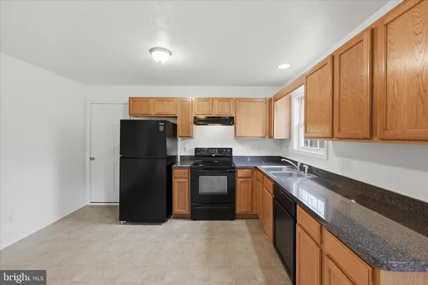 a kitchen with granite countertop a refrigerator stove and sink