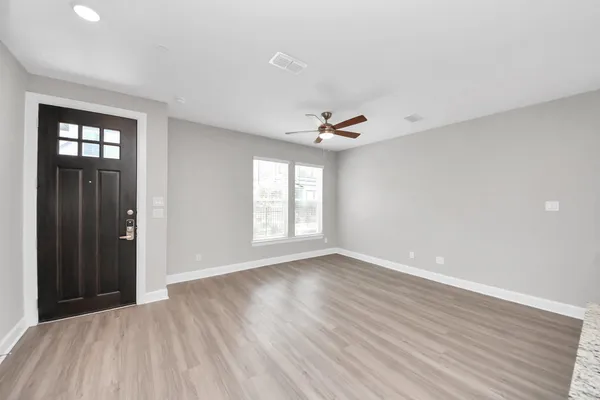 a view of an empty room with wooden floor and a ceiling fan