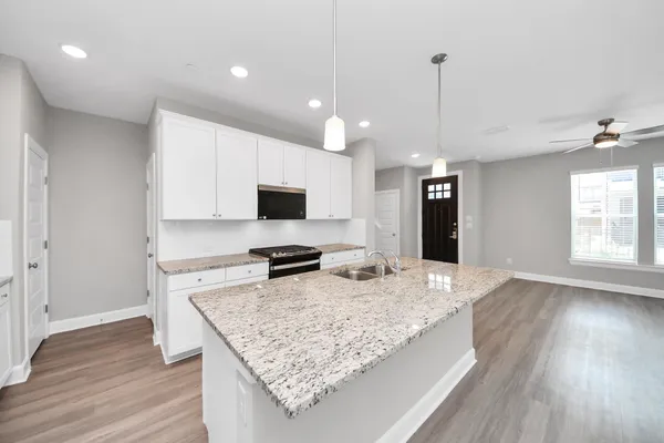 a kitchen with stainless steel appliances granite countertop a refrigerator a sink dishwasher a stove and a refrigerator with wooden floor