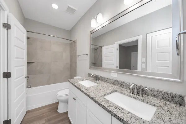 a bathroom with a granite countertop sink a toilet and shower