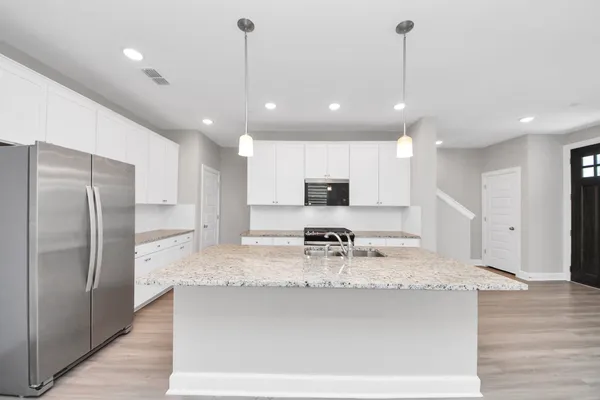 a large kitchen with kitchen island a large counter top stainless steel appliances and cabinets